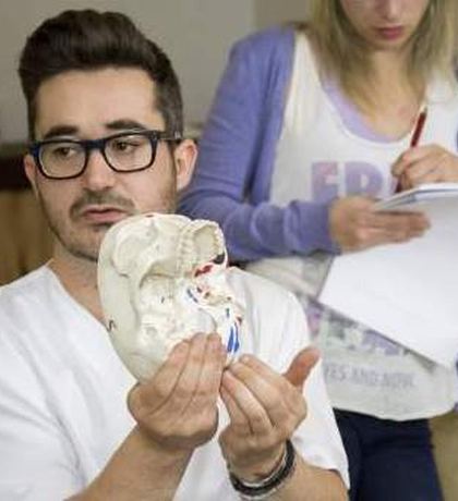 El profesor Tomás Pérez con un modelo de cráneo en una clase práctica